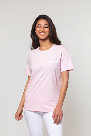 Mannequin femme, brune et souriante, les bras ballants, porte un t-shirt rose avec la mention shiny floquée coté coeur. Elle a le regard pétillant et le sourire lumineux.